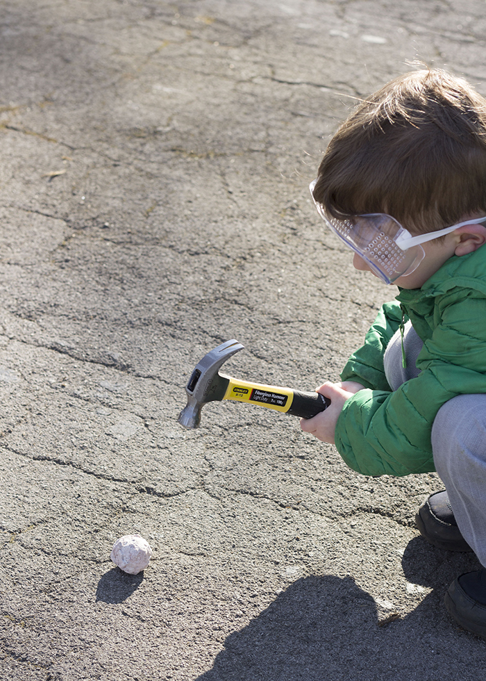 BOY WITH HAMMER HITTING ROCK